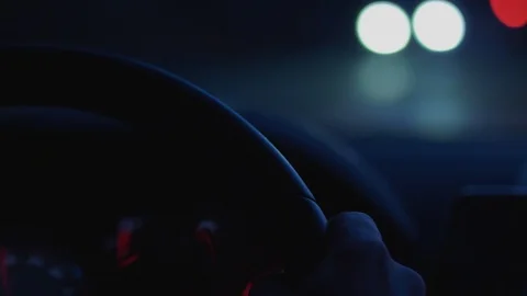 Hand on steering wheel during car driving on dark night road Stock Footage 102940574