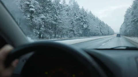 Hand on steering wheel visible of person driving car on highway in winter 스톡 동영상 145729261
