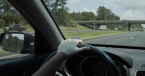 Hand on steering wheel while driving down the highway Stock Footage 229713728