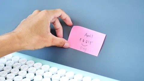 Hand sticking note with text April Fools' Day to the wall Stock Footage 269903660