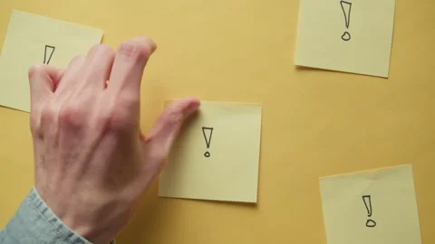 Hand sticking post it note onto yellow backdrop Stock Footage 320557694