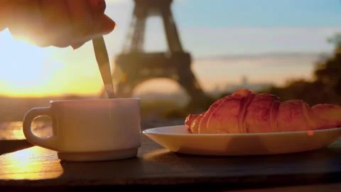 Hand stirring coffee with spoon against sunrise over Eiffel Tower Stock Footage 303423587