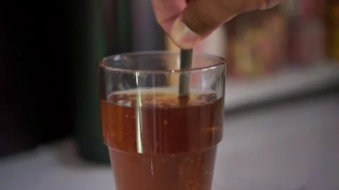 Hand stirring hot tea in a clear glass with a spoon. Stock Footage 342634245