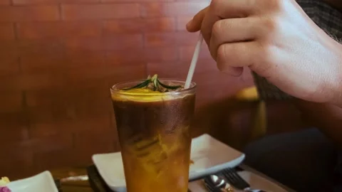 Hand stirring layered drink of espresso coffee and iced orange juice in a glass Stock Footage 315856747