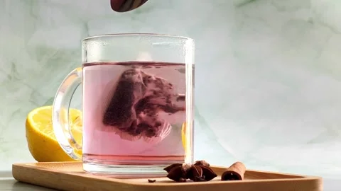 Hand stirring red herbal tea with spoon in clear glass cup, hot steam Stock-Footage 336953524
