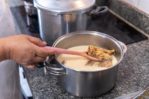 Hand stirring salted cod from the pot by removing the salt with milk Stock Photos