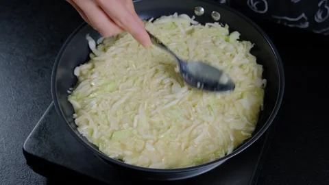 Hand Stirring Shredded Cabbage in Black Skillet Cooking Stock-Footage 341446312