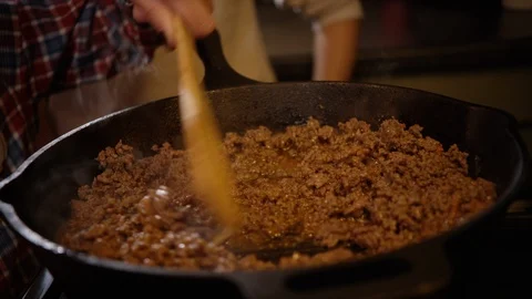 Hand stirring sizzling and frying ground beef in cast iron pan Video stock 123736211