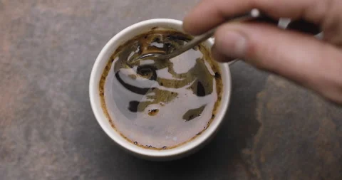 Hand stirring with a spoon of coffee in a white cup, slow motion. Stock Footage 146330108