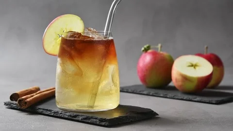 Hand stirs apple cider cold brew tonic using metal straw and mixes coffee into Stock Footage 345556930