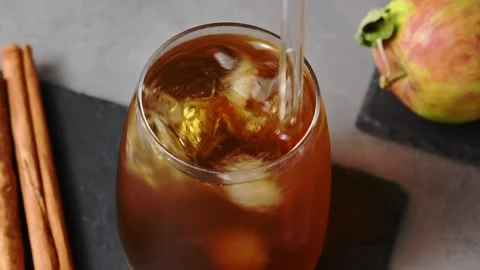 Hand stirs apple cider cold brew tonic with glass straw in close view beside Stock Footage 345557607