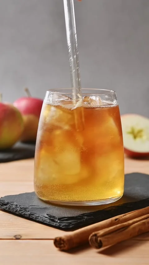 Hand stirs apple cider cold brew tonic with glass straw, blending coffee and Stock Footage 345558267