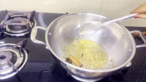 Hand stirs aromatic onion blend inside steel vessel Stock Footage 314178037