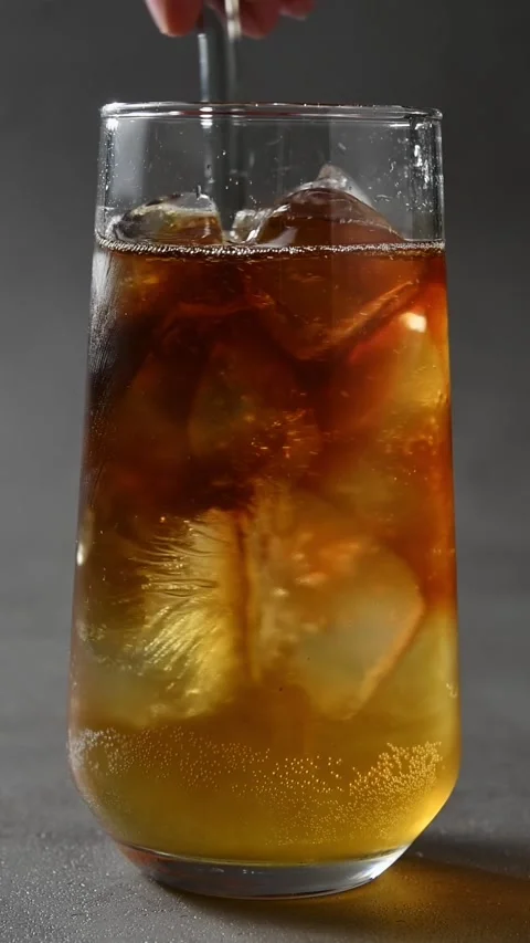 Hand stirs cold brew, apple cider and tonic with glass straw to mix layered iced Stock Footage 345486835