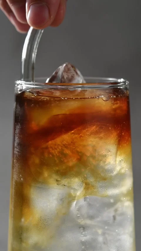 Hand stirs cold brew with apple cider and tonic over ice using metal straw as Stock Footage 345487196