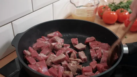 A hand stirs fried red beef meat in a frying pan. Proper nutrition, healthy food Stock Footage 262434149