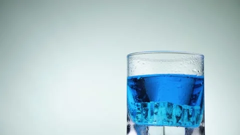 Hand stirs ice cubes and kiwi with blue lemonade using a blue straw. Stock Footage 131947970