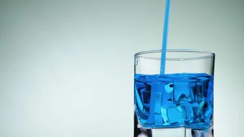 Hand stirs ice cubes with blue lemonade using a blue straw. Stock Footage 131230973
