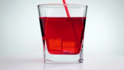 Hand stirs ice cubes with red lemonade using a red straw. Stock Footage 130464329