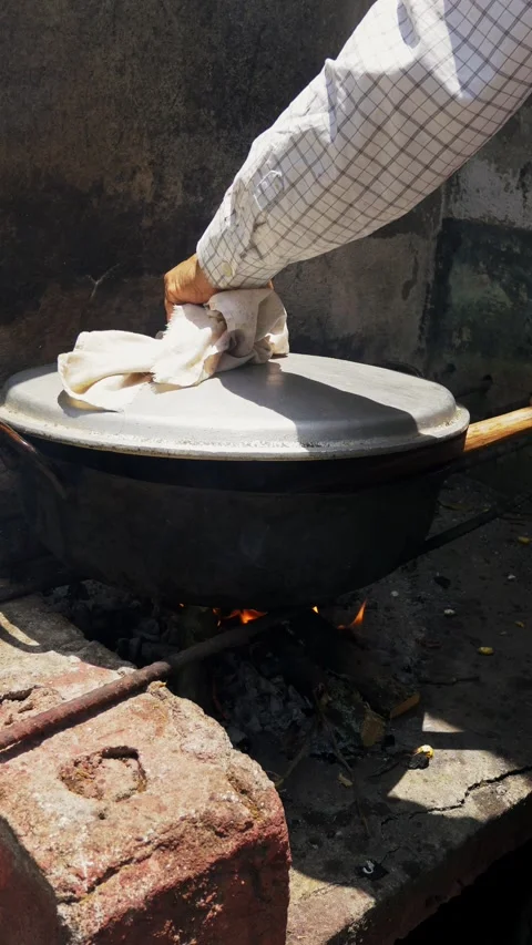 Hand stirs meat in a rusty wok over open flame Fritada Stock Footage 339638170