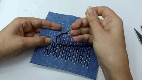 Hand stitching sashiko embroidery pattern on blue fabric Stock Photos