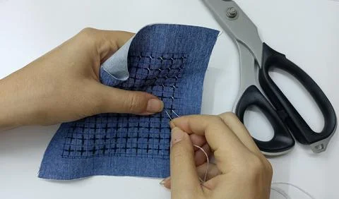 Hand stitching sashiko pattern on blue fabric with needle Stock Photos