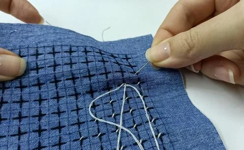Hand stitching sashiko pattern on blue fabric close up Stock Photos