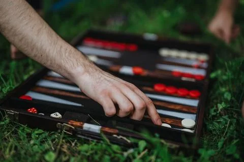 A hand strategically moves backgammon pieces during an outdoor game Stock Photos