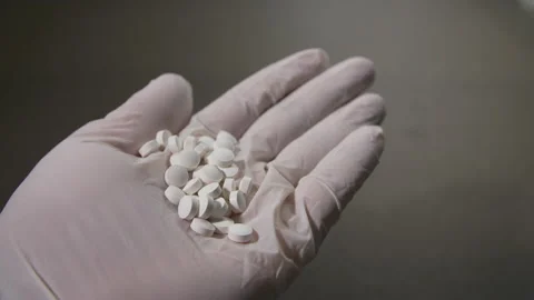 A hand is stretched out offering many pills, pharmaceutical or illegal drugs Stock Footage 154383907