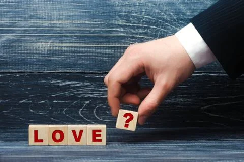 The hand stretches a cube with the question mark symbol to the word love. Fotos de archivo