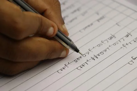 Hand of student writing computer programs on paper with black pen Stock Photos