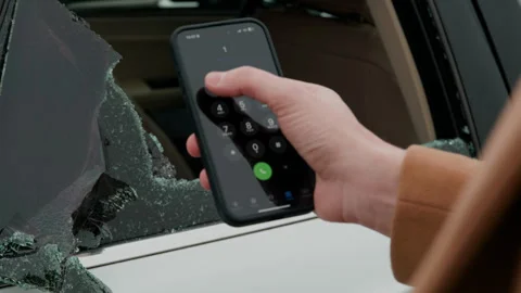 Hand swiftly dials 112 after noticing broken car window action for emergency Stock Footage 276091876