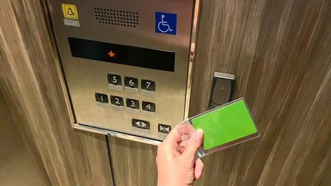 A hand swipes an RFID card at a reader in an elevator in a modern condominium. Stock Photos