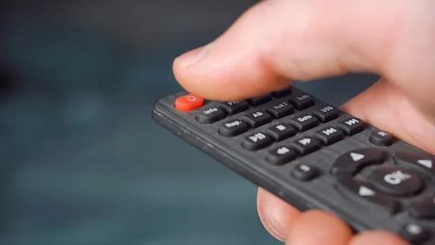 Hand is switch OFF tv on remote control, close-up Stock Photos