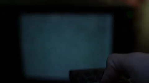 The hand switches channels on the remote control in the foreground, there is no Stock Footage 234617152