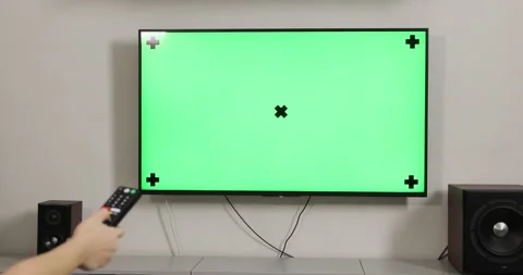 Hand switches channels using the remote control with TV on green screen Stock Footage 148066615