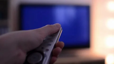 The hand switches TV remote control with finger, viewing of TV programs, re.. Stock Footage 257875347