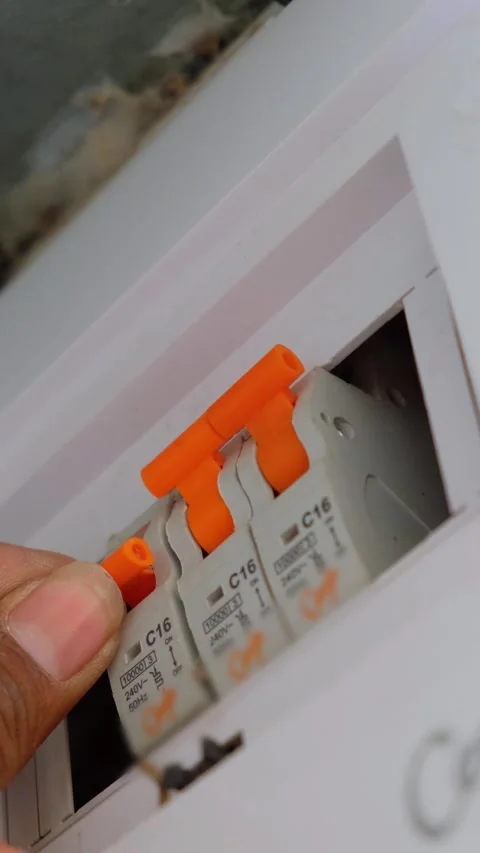 Hand switching an orange MCB lever in a residential circuit breaker panel Vídeo Stock 332998032