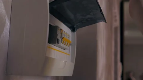 Hand switching power switch on a fusebox. Close up of electrician checking fuse Video stock 236299125