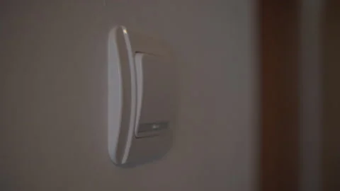 A hand switching on a wall light switch Stock Footage 339196069
