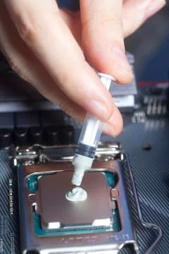 Hand with syringe applying thermal paste on the CPU processor on motherboard 写真素材