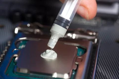Hand with syringe applying thermal paste on the CPU processor on motherboard Stock Photos