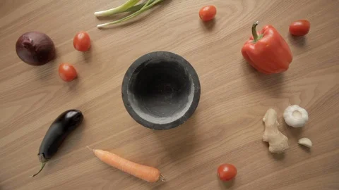 Hand take and return pestle in mortar at wooden table with pestle and veggies 스톡 동영상 115368276