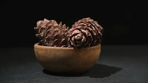 Hand takes and puts cedar cone in wooden bowl on black background. Superfood Stock Footage 239278657