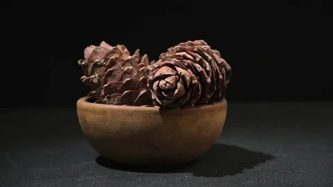 Hand takes and puts cedar cone in wooden bowl on black background. Superfood Stock Footage 240396394