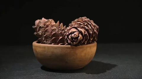 Hand takes and puts cedar cone in wooden bowl on black background. Superfood Stock Footage 241927640