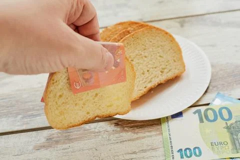 A hand takes bread using euro banknotes instead of a napkin, bread price incr Stock Photos