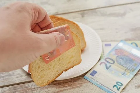 A hand takes bread using euro banknotes instead of a napkin, bread and money, Stock Photos