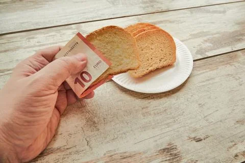 A hand takes bread using euro banknotes instead of a napkin, bread price incr Stock Photos