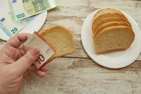 A hand takes bread using euro banknotes instead of a napkin, bread price incr Stock Photos
